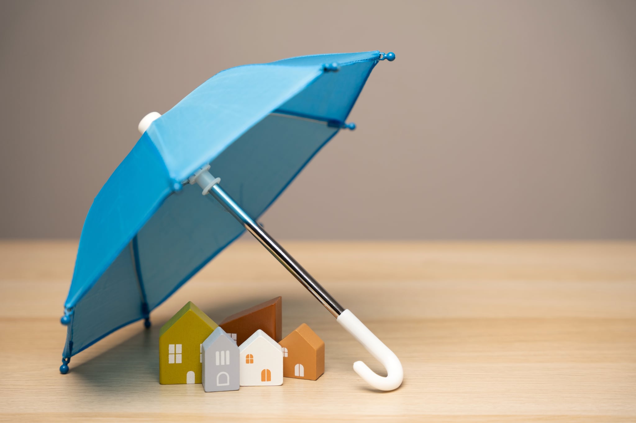 Home insurance concept with a small house under an umbrella